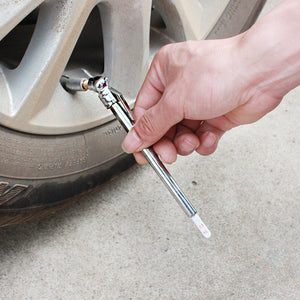 Hand pressing the pencil tire gauge onto a car valve, white scale stick pushed out of the barrel