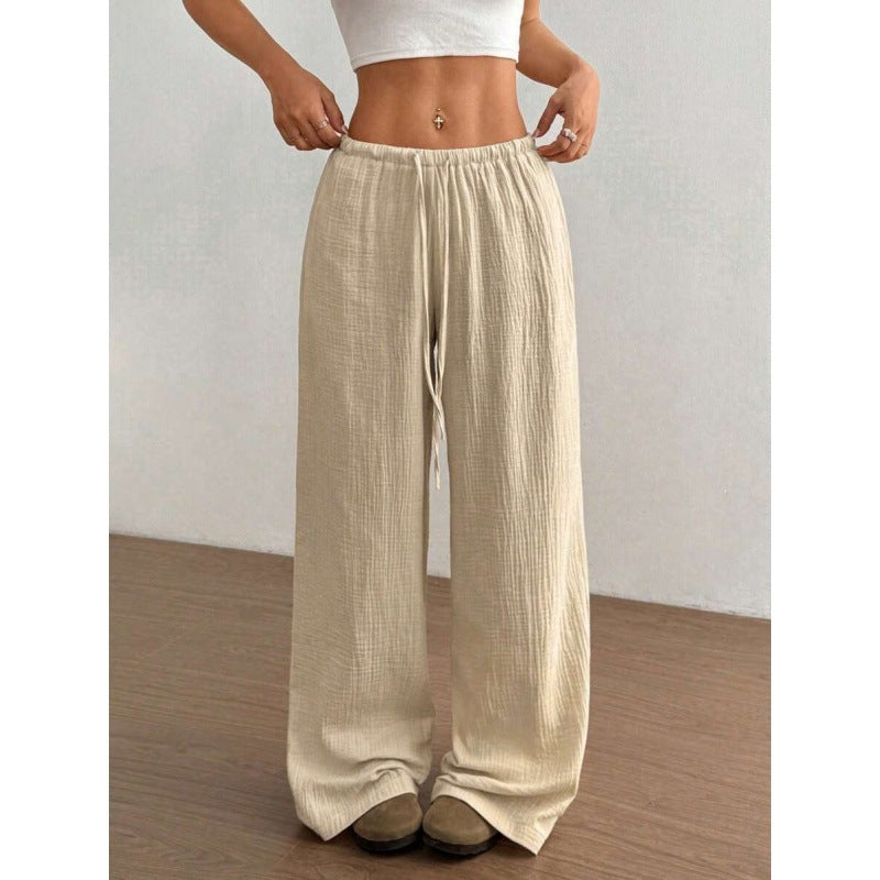 Woman wearing loose wide leg cotton trousers with a soft crinkle texture and tied waist
