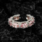 Open eternity style band lined with oval pink simulated stones and clear pave, dark background