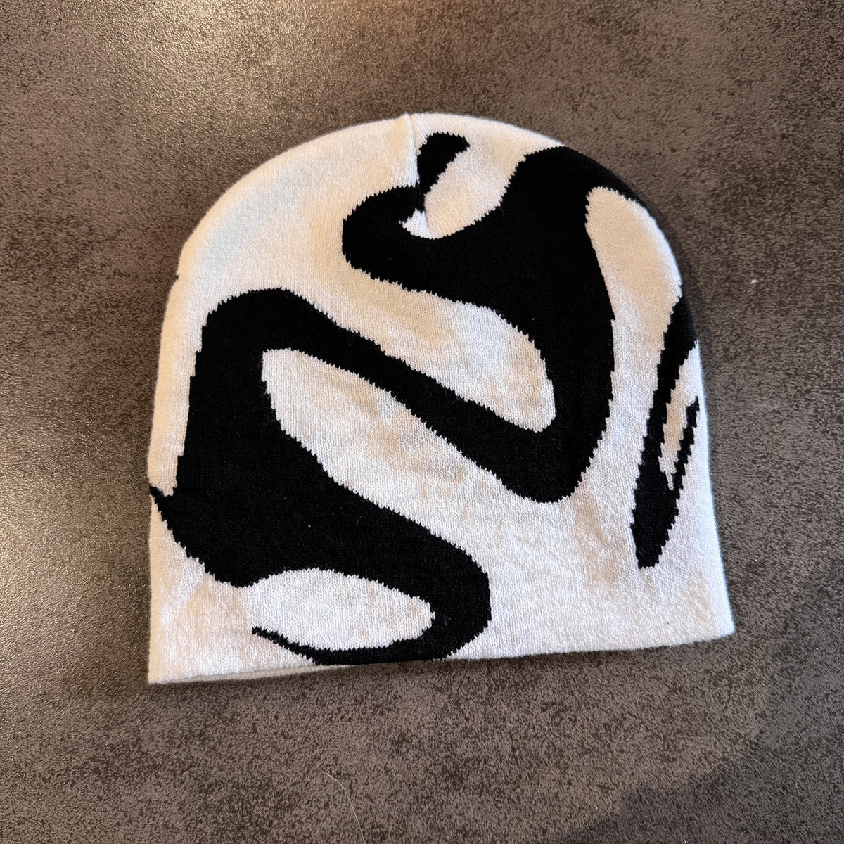 Ghost pattern knit winter beanie in black shown on a plain surface