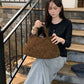 Woman holding the Matte brown woven handbag on outdoor steps, Matte brown variant