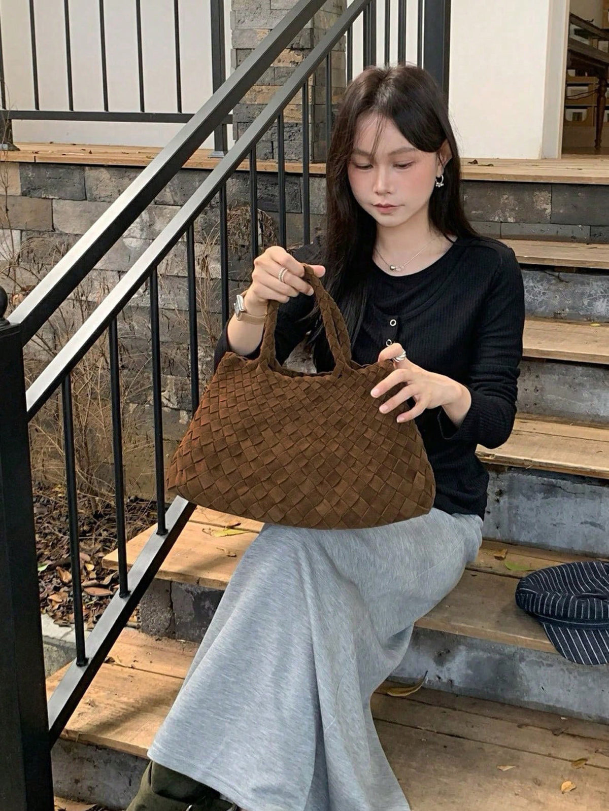 Woman holding the Matte brown woven handbag on outdoor steps, Matte brown variant