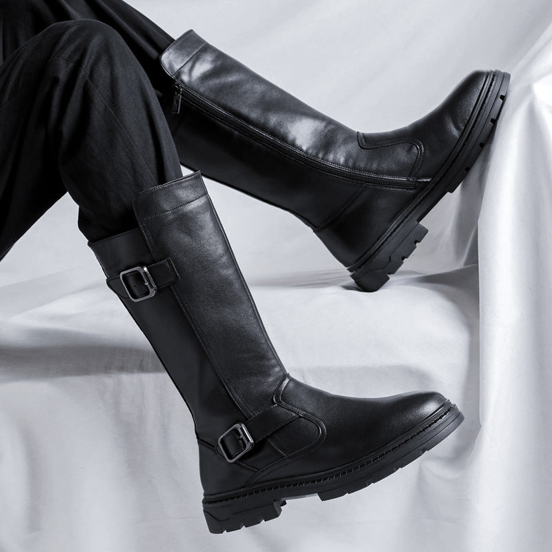 Man seated with legs crossed in tall black buckle boots with chunky lug soles
