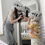 Woman and child wearing the grey dinosaur skeleton plush hood in front of a mirror