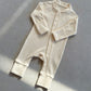Cream zip front baby romper laid flat on a gray floor, image of the 59 cm, 0 to 3 months size option