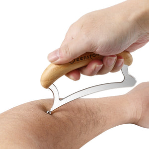 Gua sha scraping tool drawn along a forearm showing the steel edge in use