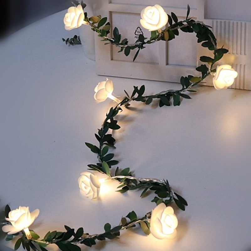 Decorative LED flower fairy string lights on a green leaf vine glowing warm, lifestyle photo