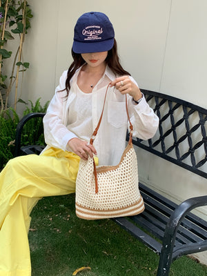 Open weave woven shoulder bag in cream with tan stripe bands and gold buckles