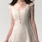 Top down layout of the cream white lace patchwork summer dress flat on a plain surface