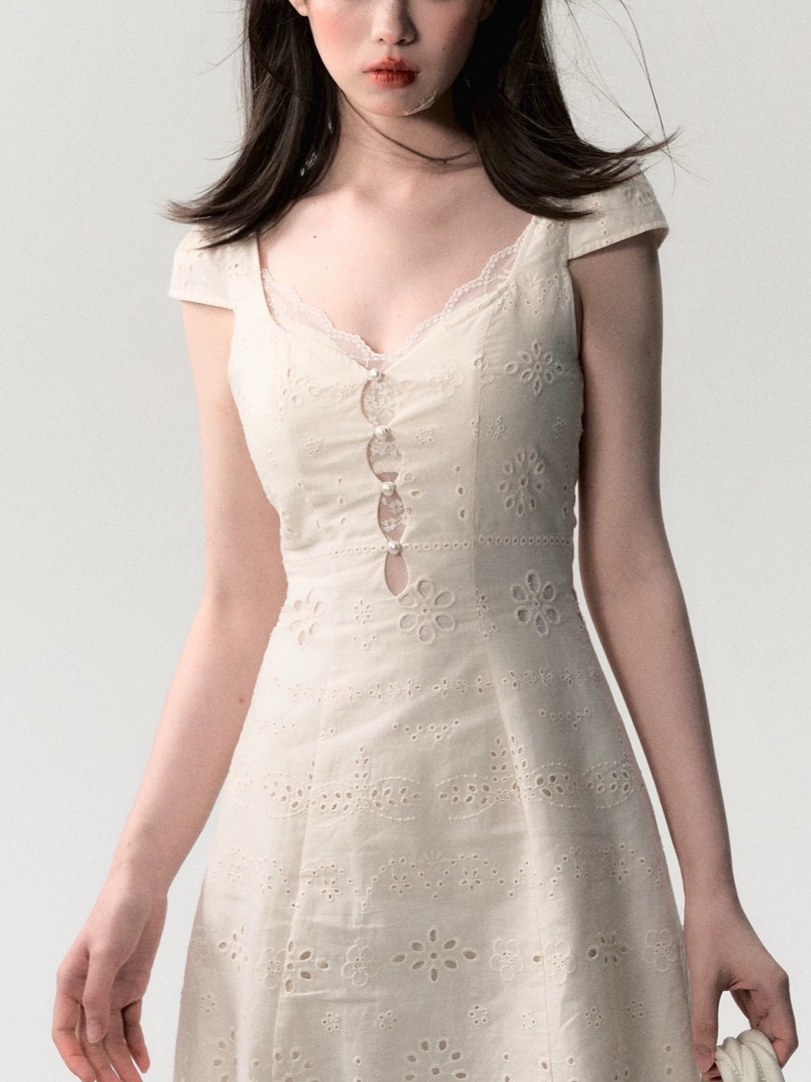 Top down layout of the cream white lace patchwork summer dress flat on a plain surface