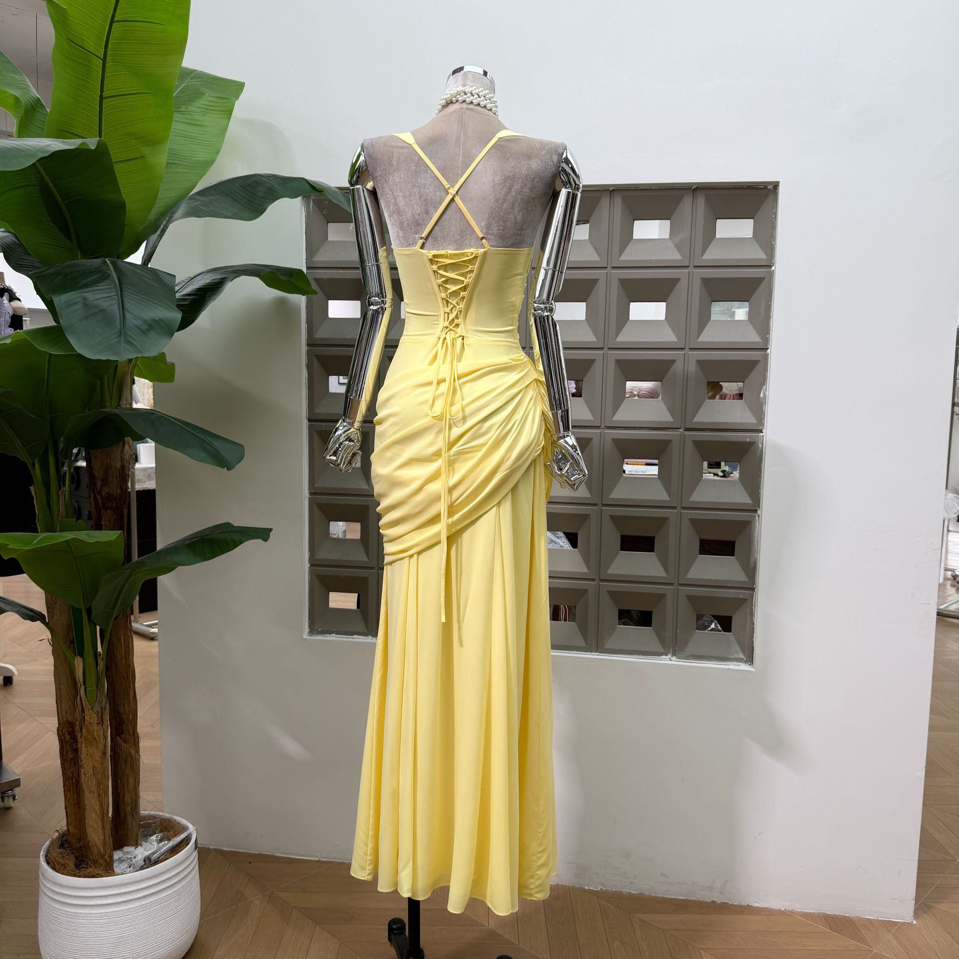 Back of the butter yellow maxi dress showing crossed straps and a laced panel with a long tie
