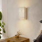 Natural travertine wall light showing pitted cream stone grain in close detail