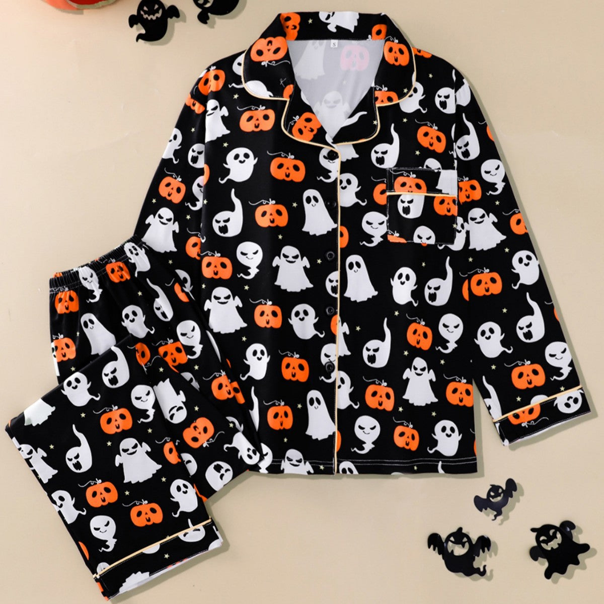 Black Halloween pajama set with orange pumpkins and white ghosts, shirt and pants laid flat