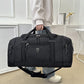 Person holding a black Oxford cloth travel duffel bag by its padded top handles