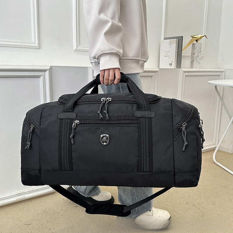 Person holding a black Oxford cloth travel duffel bag by its padded top handles