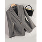 Grey herringbone tweed blazer on a hanger, front view with notch lapel and dark lining, black handbag beside it