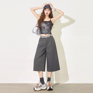 Woman in dark gray cropped wide leg suit pants with belt and sneakers front view