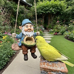Hanging resin gnome bird feeder on a rope swing with a budgie feeding from the seed bowl