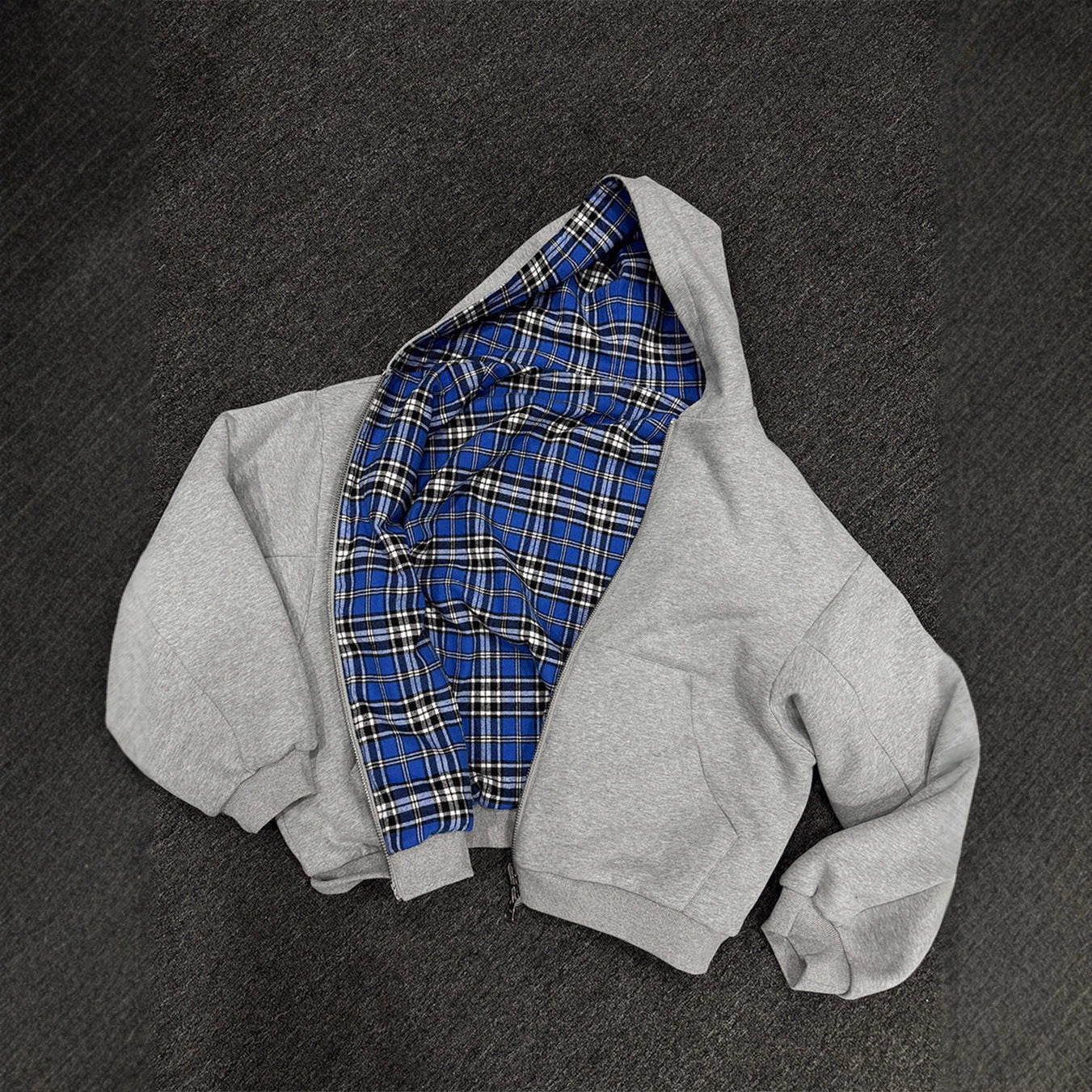Grey reversible zip hooded sweatshirt, solid grey outer with a blue tartan plaid reverse