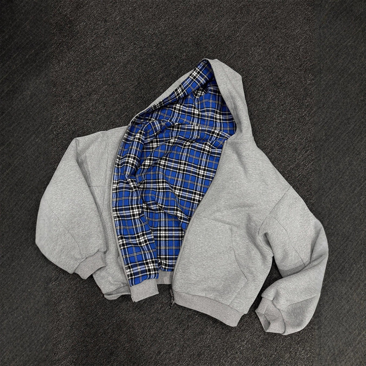 Grey reversible zip hooded sweatshirt, solid grey outer with a blue tartan plaid reverse