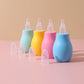 Blue manual baby nasal aspirator squeeze bulb with a soft rounded TPE tip on a pink surface
