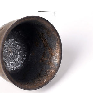 Top down view into the tea cup showing the dark speckled glaze and lighter crystalline base inside