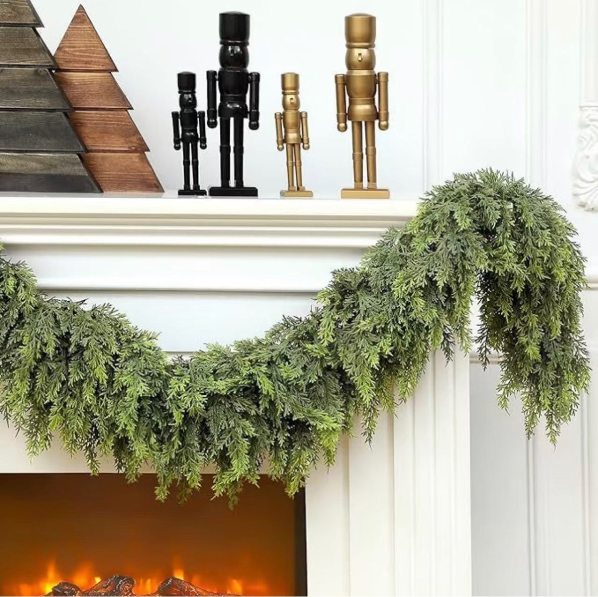Cedar garland draped along a white mantel with wooden nutcrackers and a lit fireplace below it