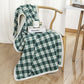 Green and white plaid coral fleece blanket in 100 x 140 cm draped over a wooden chair