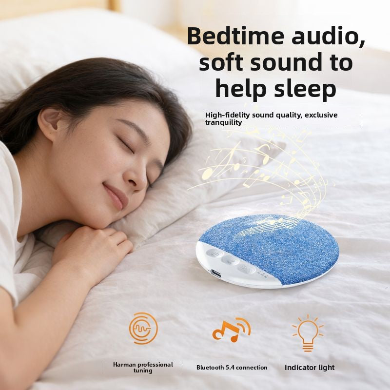 Bedside scene with a blue pillow speaker resting on a duvet beside a sleeper