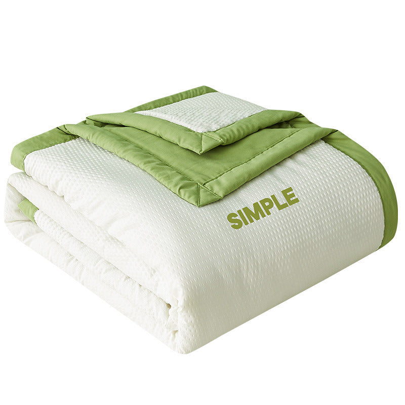 White seersucker summer cooling quilt with a colored border draped on a styled bed