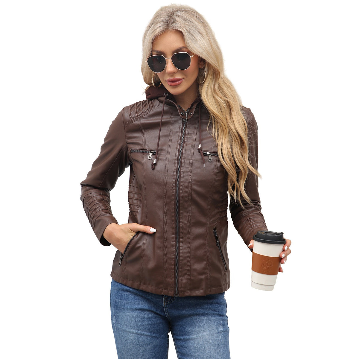 Woman in a coffee brown PU leather jacket with hood, hand in a pocket, holding a takeaway cup