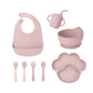 Pink 8-piece baby feeding set with a bib, a sippy cup, a bowl, four utensils and a bear paw plate