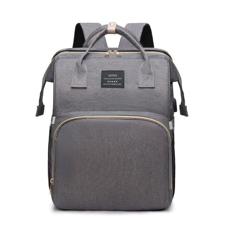 Gray diaper backpack front view with two top handles, a woven label, a front zip pocket and padded back straps