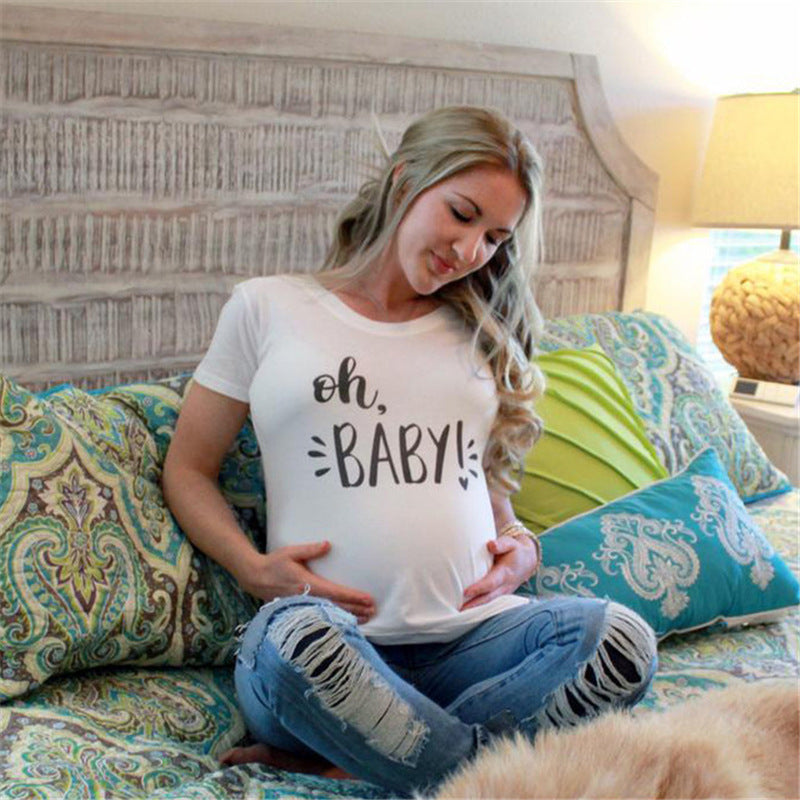 White maternity short sleeve tee with an Oh Baby print, round neck and side ruching, on a pregnant model