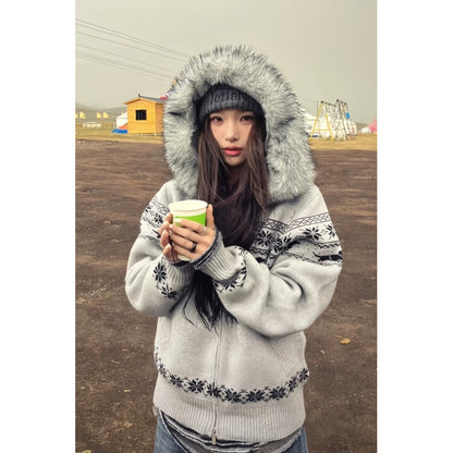 Grey Fair Isle knit cardigan with faux fur hood zipped on a woman holding a paper cup, front view