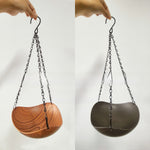 Hanging wooden bird bath swaying from maple branch