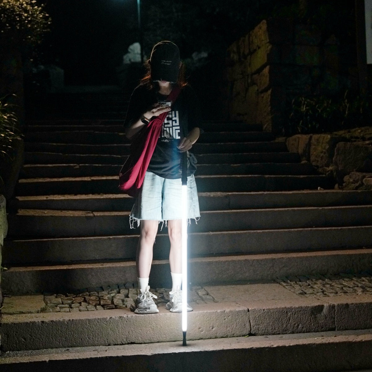 Person on stone steps at night walking with the lit white LED trekking pole