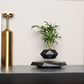 Black faceted pot with an artificial plant floating above a powered magnetic base