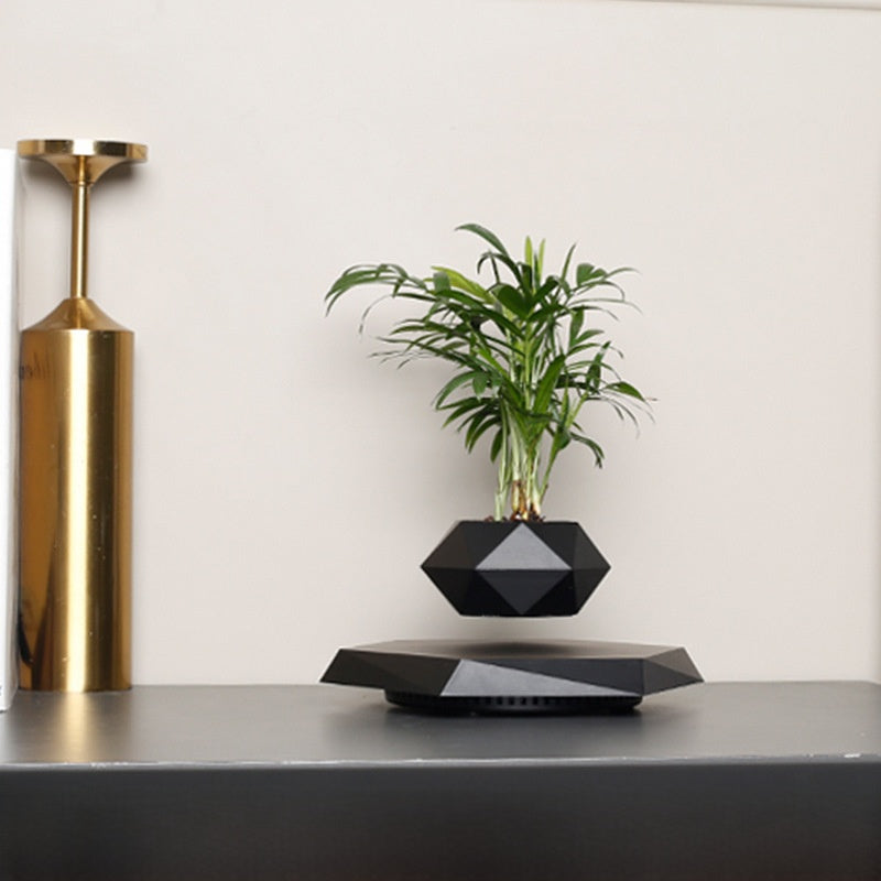 Black faceted pot with an artificial plant floating above a powered magnetic base