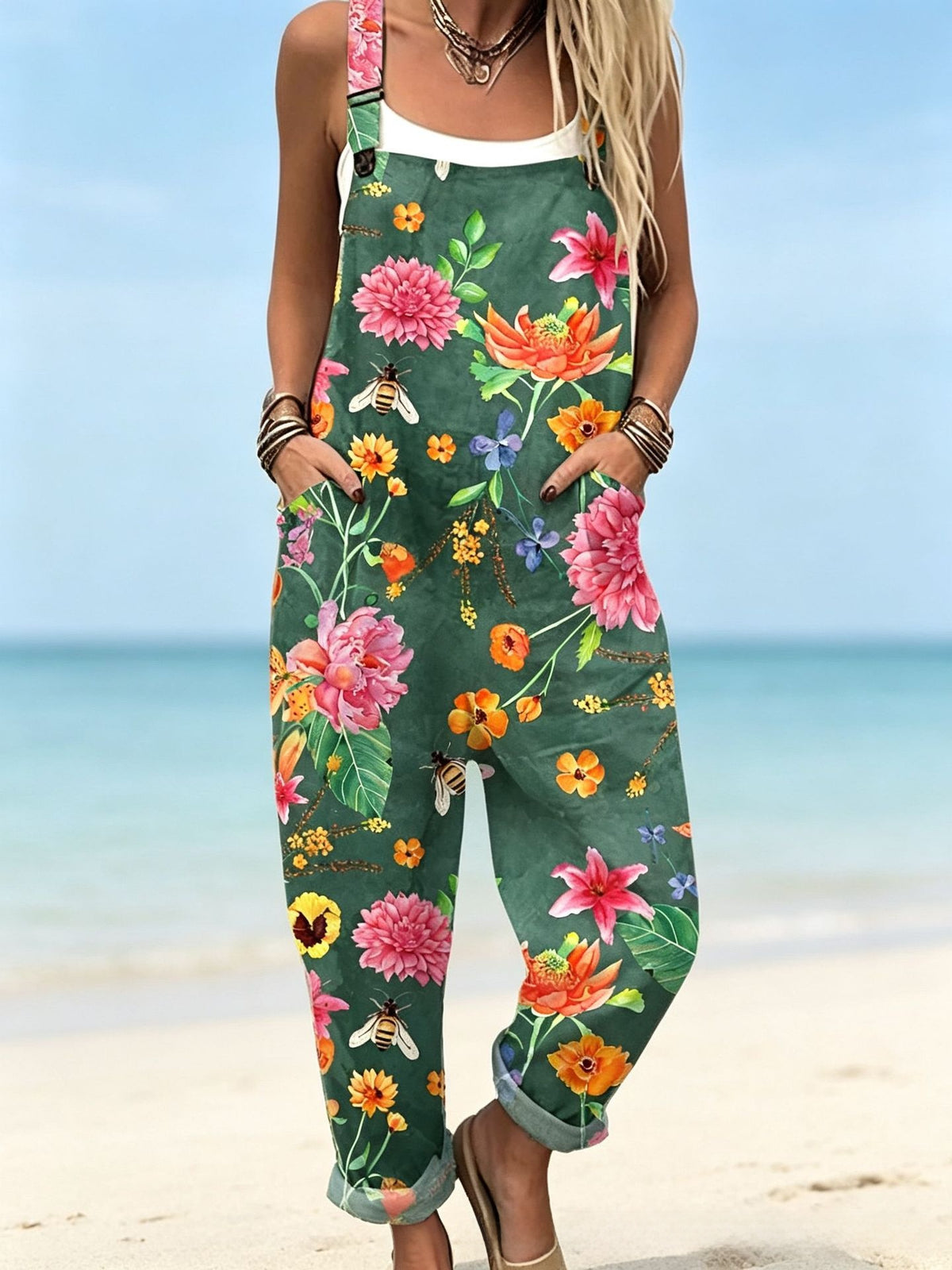 Size L option: Dark green overalls with a pink and orange floral print, cuffed legs and pockets on a beach