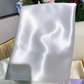 Ice silver glossy silk pillowcase draped on a cream sofa