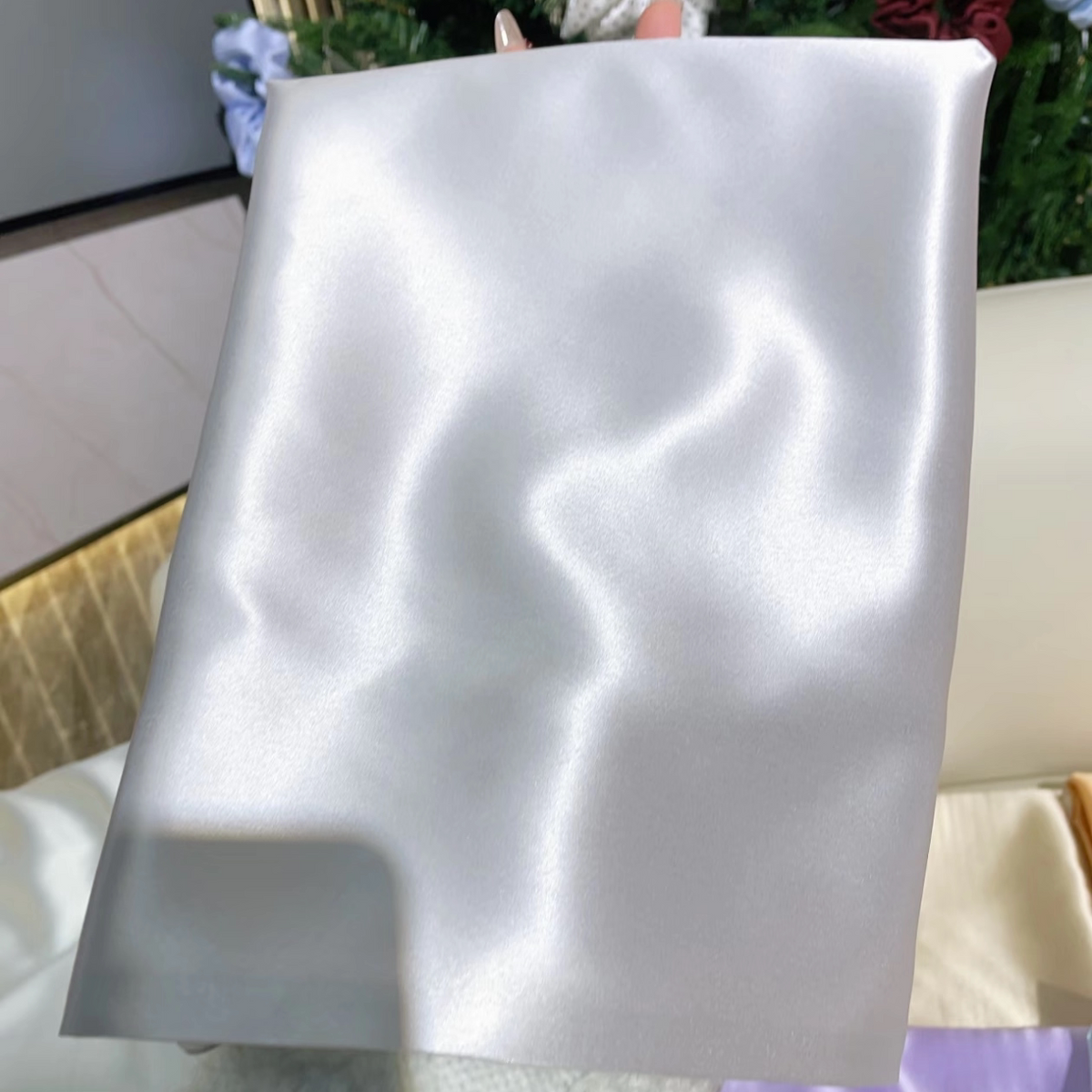 Ice silver glossy silk pillowcase draped on a cream sofa