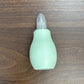 Brown and pink baby nasal aspirator bulbs with soft tips shown together on a pastel surface