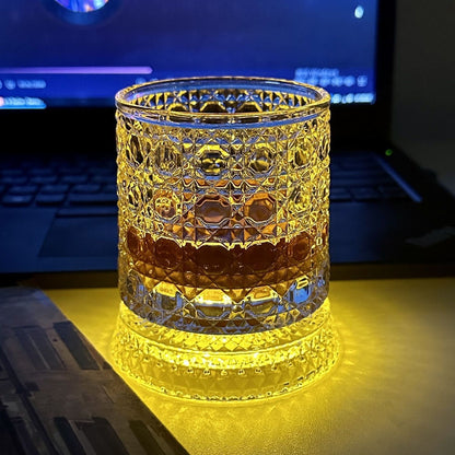 Cut glass whiskey tumbler on a dark desk, amber LED pad lighting the faceted base from below