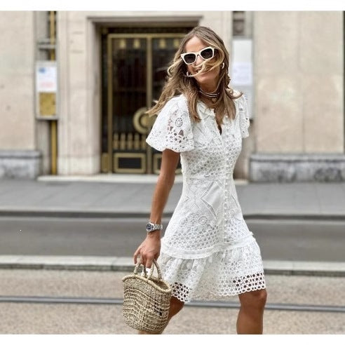 Woman in white eyelet lace bodycon short dress walking with a woven straw bag