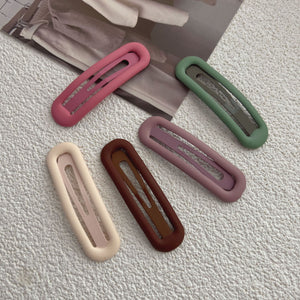 Solid color matte snap hair clips grouped on a cream surface