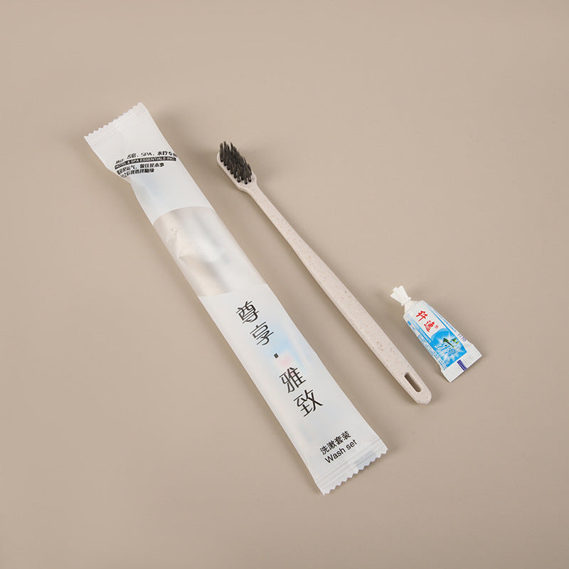 Beige straw toothbrush with charcoal bristles, toothpaste tube and a wash set pouch