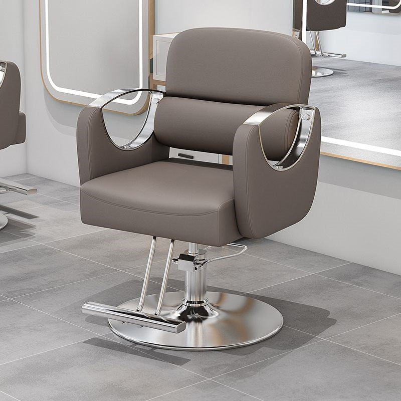 Light beige salon styling chair with silver metal armrests and a hydraulic column base