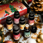 Six Christmas scented essential oil bottles beside a festive Merry Christmas gift box