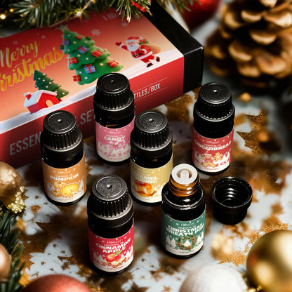 Six Christmas scented essential oil bottles beside a festive Merry Christmas gift box